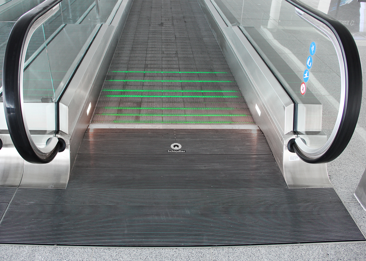 The visually flat overall impression of the moving walk with its continuous glass balustrade and matt stainless steel cladding refers to the very flat design of the substructure, which means that the moving walk can be placed cost-effectively directly on the sub-floor of the building without any on-site changes. The passenger is safely guided across the moving walkway along green and red light strips. Schindler Aufzüge AG - moving walk - passenger transport - designship GmbH - product design - industrial design - machine design - interface design - iF world design index - Top 25 Industry - Top 100 design studios worldwide - we love design