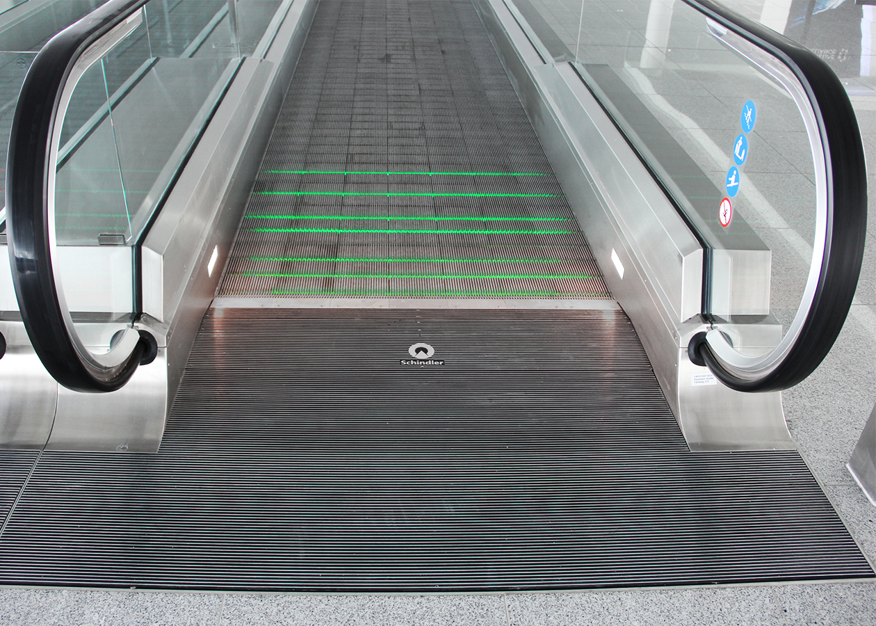 A flowing transition lets passengers glide over the treadmill - modern moving walk from Schindler Aufzüge AG The visually flat overall impression of the moving walk with its continuous glass balustrade and matt stainless steel cladding refers to the very flat design of the substructure, which means that the moving walk can be placed cost-effectively directly on the sub-floor of the building without any on-site changes. The passenger is safely guided across the moving walkway along green and red light strips. Schindler Aufzüge AG - moving walk - passenger transport - designship GmbH - product design - industrial design - machine design - interface design - iF world design index - Top 25 Industry - Top 100 design studios worldwide - we love design